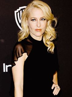 a woman with blonde hair wearing a black dress and posing for the camera at an event