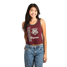 a young woman is smiling and wearing a maroon tank top with hogwart's logo on it