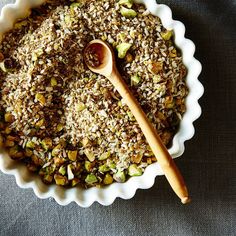 a bowl filled with food next to a wooden spoon on top of a gray table