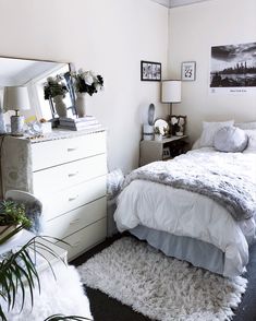 a bedroom with a bed, dresser and mirror on the wall next to planters