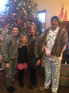 three people standing in front of a christmas tree