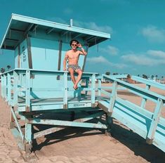 a man sitting on top of a blue lifeguard tower