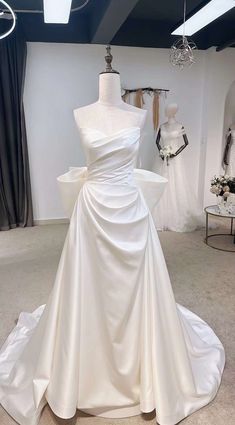 a white wedding dress on display in a bridal room with mannequins