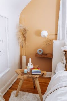 a small table with some books on top of it next to a bed in a room