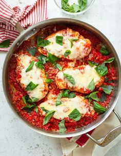 a pan filled with chicken parmesan and sauce on top of a white table