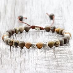 ◈ This beautiful Tibetan bracelet is carefully handcrafted with jasper rhodonite beads and high quality wooden beads. Each bead has been individually selected to ensure beauty and durability. This handcrafted men's bracelet is a versatile accessory that can complement any outfit. The wooden beads used in this bracelet have a rustic, natural charm. Each has a unique pattern and texture, making each bracelet a special and unique piece. These beads are strung on sturdy thread that has been skillful Adjustable Nature-inspired Bracelet With Round Beads, Bohemian Jasper Round Bead Bracelets, Adjustable Hand-wrapped Agate Bracelets, Adjustable Natural Stone Beaded Bangle Bracelet, Adjustable Hand Wrapped Agate Bracelets, Adjustable Beaded Nature-inspired Bracelet, Adjustable Bracelets With Natural Stones, Adjustable Natural Stone Bracelets, Bohemian Style 8mm Beaded Wristband Bracelet