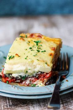 a blue plate with a slice of vegetarian moussaka on it next to a fork