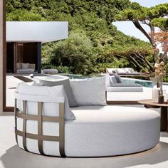 an outdoor living room with white furniture and trees in the backgroung area