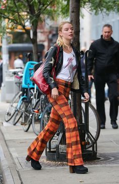 a woman is walking down the street in plaid pants