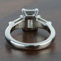 a close up of a ring on top of a wooden table with a diamond in the center