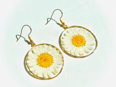 These are real dried and pressed daisies set into clear resin and placed into an earring. White Round Pressed Flower Earrings, White Resin Earrings With Pressed Flowers, White Pressed Flower Round Earrings, Handmade Gold Daisy Earrings, Daisy Resin Earrings, Handmade Daisy-shaped Earrings For Gifts, Yellow Flower Earrings With Pressed Flowers, Cheap Flower-shaped Earrings With Pressed Flowers, Yellow Flower-shaped Earrings With Pressed Flowers