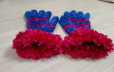 two red and blue mittens sitting on top of a bed