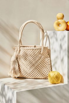 a white purse sitting on top of a counter next to some fruit and doughnuts