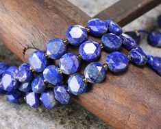 a bunch of blue beads sitting on top of a wooden stick next to a piece of wood