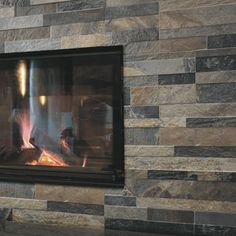 a fireplace with a fire burning inside of it next to a wall mounted stone heater