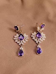 The earrings are three tiered with tear drop one and two carat amethyst stones and a zircon accented deco design.  Total 4 carats amethyst.  .88 carats zircon.  14K gold plated. Luxury Amethyst Teardrop Earrings, Elegant Purple Earrings For Pierced Ears, Elegant Amethyst Earrings For Formal Occasions, Purple Fine Jewelry Earrings For Formal Occasions, Formal Amethyst Drop Earrings, Elegant Purple Drop Earrings, Elegant Amethyst Drop Earrings, Elegant Amethyst Earrings For Party, Elegant Purple Jewelry For Evening