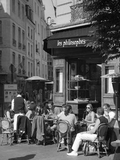 black and white photograph of people sitting at tables outside