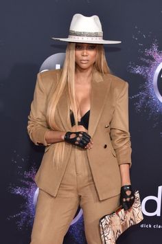 nicki hilton at the american music awards wearing a tan suit and hat with black gloves