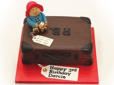 a teddy bear sitting on top of a suitcase cake