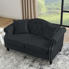 a black couch sitting on top of a rug in a living room next to a window