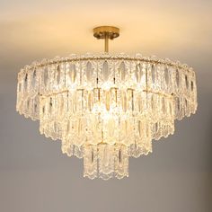 a crystal chandelier hanging from the ceiling in a room with gray walls and flooring