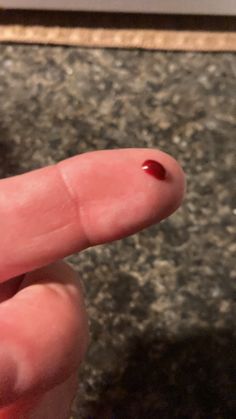 a finger with a tiny red substance on it