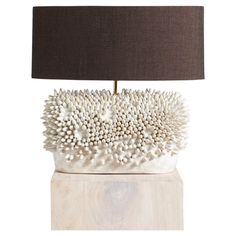 a table lamp with a brown shade on it and a white sculpture in the middle