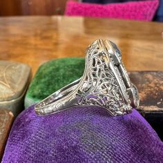 an antique diamond ring sitting on top of a purple cloth in front of a wooden table