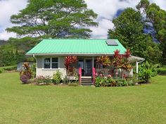 a small white house sitting in the middle of a lush green field