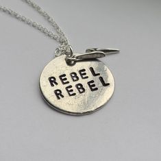 a silver necklace with the words rebel on it