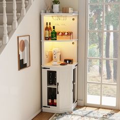 a white cabinet with wine bottles in it next to a stair case that has an open door