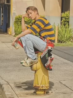 a boy sitting on top of a yellow fire hydrant