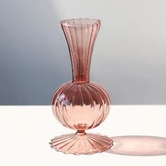 a pink glass vase sitting on top of a white table