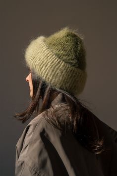 a woman with long hair wearing a green knitted hat on her head and looking off to the side