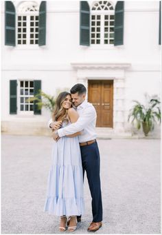 a man and woman hugging in front of a white building