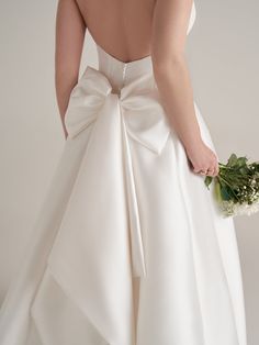 the back of a bride's wedding dress with a large bow at the waist