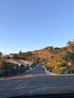 an empty street with houses on the hill in the background