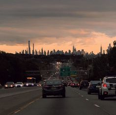 cars driving down the highway in front of a city skyline