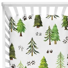 a white crib with green trees and paw prints