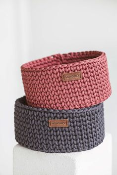 three knitted baskets sitting on top of each other, one is pink and the other is grey