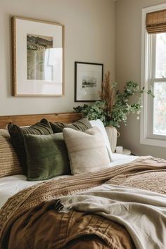 a bed with pillows and blankets on top of it next to a window in a bedroom