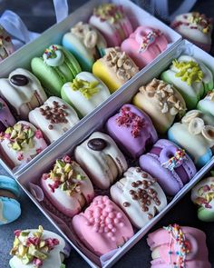 two boxes filled with different colored cupcakes on top of a table next to each other