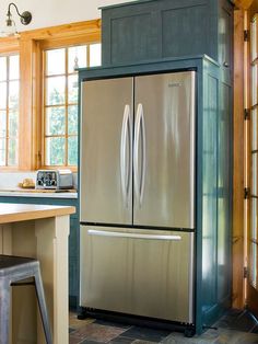 a large metallic refrigerator freezer sitting in a kitchen next to a table and chairs