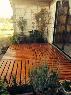 a wooden deck with potted plants on it and a sliding glass door to the outside