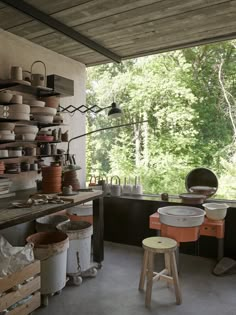 an outdoor kitchen with pots and pans on the shelves, stools and table