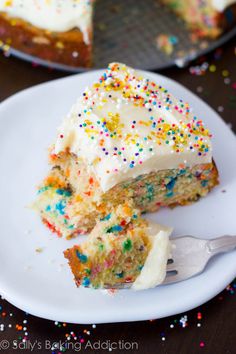 a slice of cake with white frosting and sprinkles on a plate