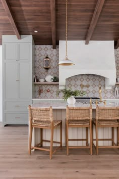 a kitchen with two chairs and a stove in the center, surrounded by wooden flooring