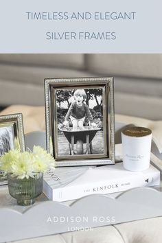 a coffee table with two pictures and a cup on it, next to some books