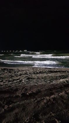 there is a surfboard on the beach by the water's edge at night