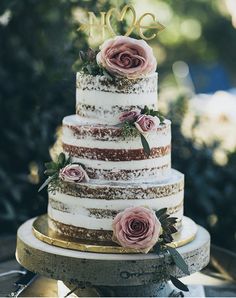 a three tiered cake with pink flowers on top and the word love spelled in gold